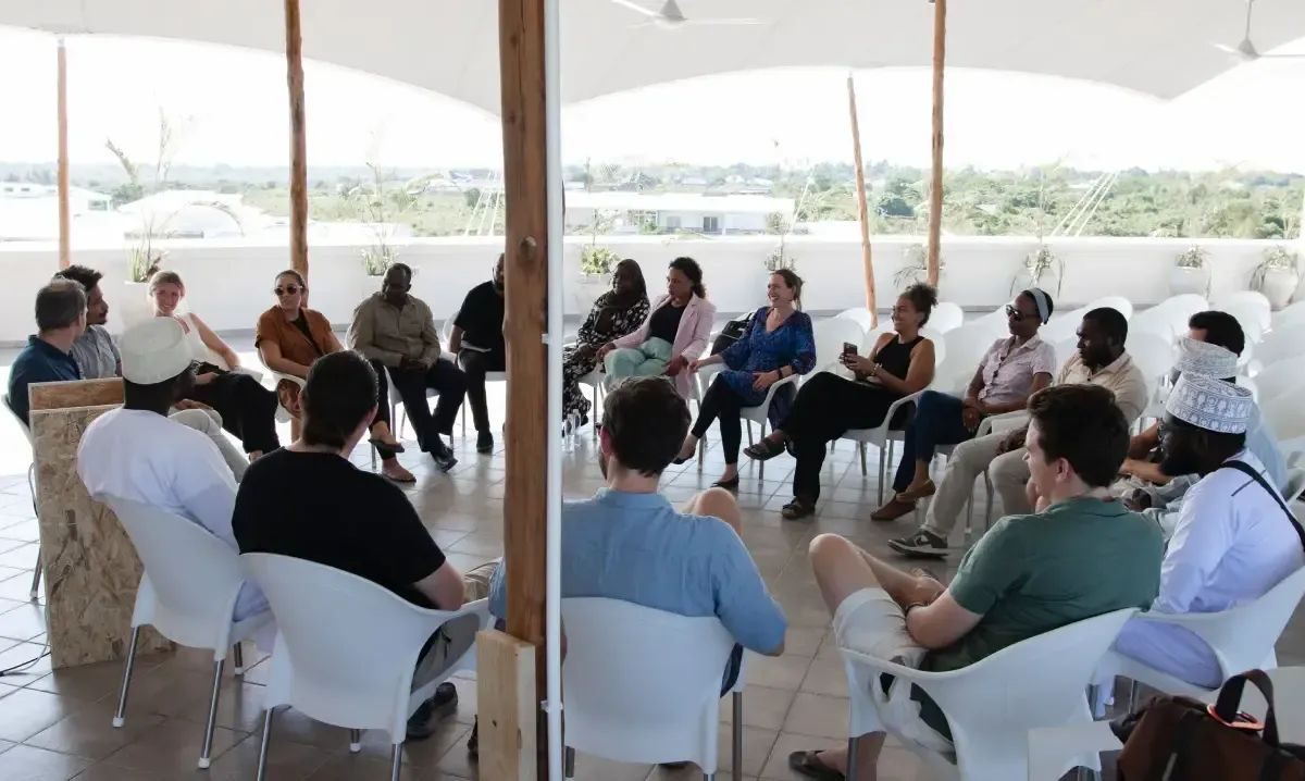 Fellows and founders in a circle discussion under a canopy
